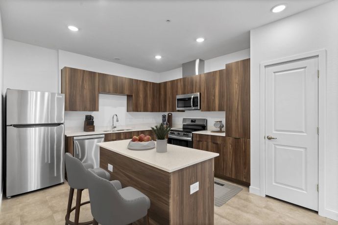 Mesa Vista Affordable Apartments with Modern kitchen with wood cabinets, stainless steel appliances, and an island with two gray chairs.