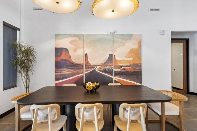Mesa Vista Affordable Apartments with Modern dining room with a black table, six chairs, and a desert landscape triptych on the wall.