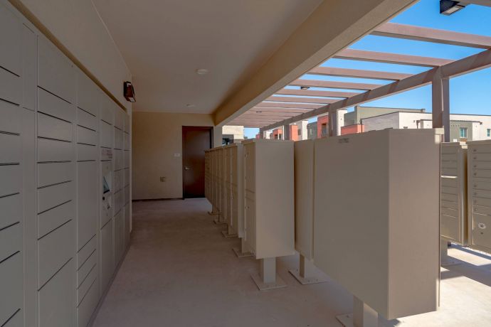 Mesa Vista Affordable Apartments with Outdoor mail and package lockers under a canopy, with apartment buildings visible in the background.