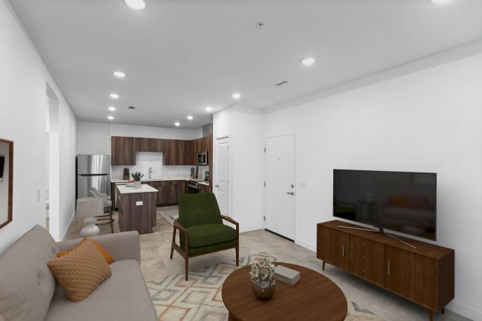 Mesa Vista Affordable Apartments with Modern apartment living room with sofa, armchair, TV, and open kitchen in the background.