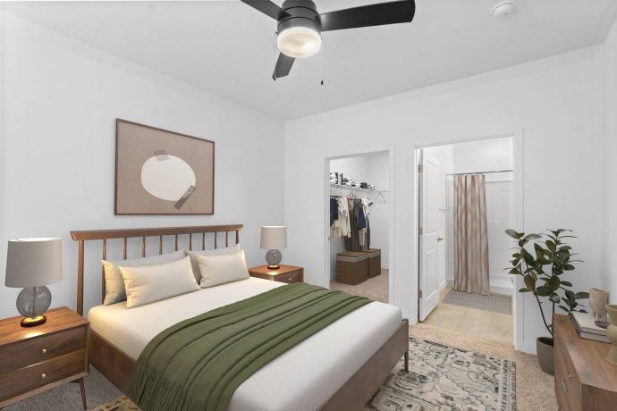 Mesa Vista Affordable Apartments with A modern bedroom with a wooden bed, green blanket, nightstands, ceiling fan, and a view into a closet and bathroom.