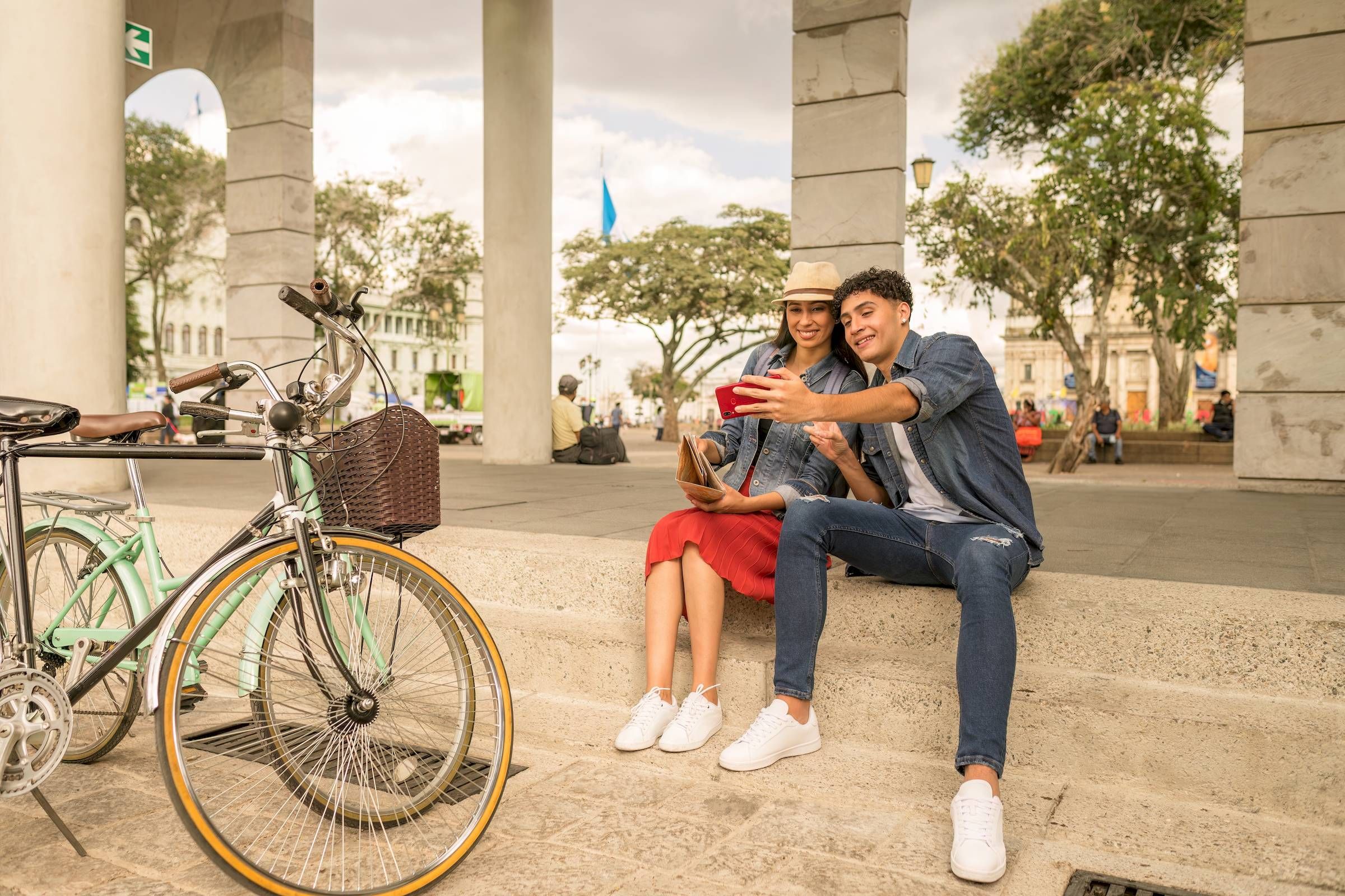 Mesa Vista Affordable Apartments with A smiling couple sits on steps, taking a selfie with a smartphone beside a parked bicycle outdoors.